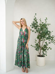 Woman in a floral dress standing next to a potted plant on a white background